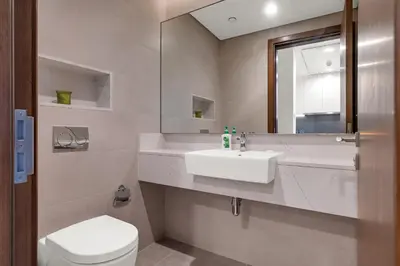a bathroom with a sink and a toilet and a mirror at CanalFront - Central Location up to 7 Guests in Dubai
