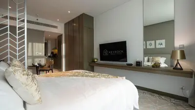 a bedroom with a white bed and a tv on a wall at Keyrock Damac Maison Privée - Studio in Business Bay with Pool, Gym & Free Parking in Dubai
