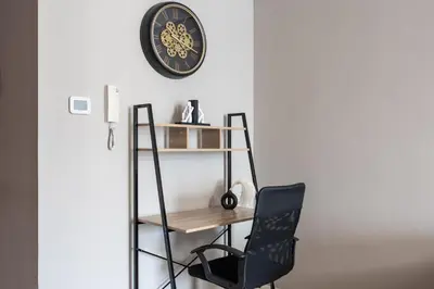 a desk and chair next to a wall with a clock at Luxury JLT Studio Lake View Metro 5minMarina in Dubai