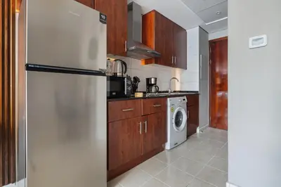 a kitchen with a refrigerator and a washer and dryer at Luxury JLT Studio Lake View Metro 5minMarina in Dubai