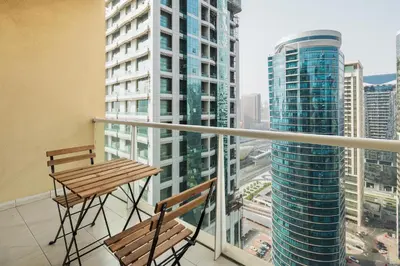 a balcony with two chairs and a view of a city at Luxury JLT Studio Lake View Metro 5minMarina in Dubai