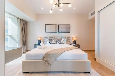 a white bedroom with a large bed and a chandelier at Upgraded 2BR with Partial Sea View Near to Dubai Tram, Elite Residence, Dubai Marina by Deluxe Holiday Homes in Dubai