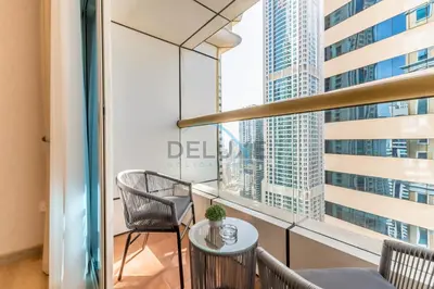 a balcony with chairs and a table in front of a window at Upgraded 2BR with Partial Sea View Near to Dubai Tram, Elite Residence, Dubai Marina by Deluxe Holiday Homes in Dubai
