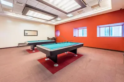 two pool tables in a room with orange walls at Upgraded 2BR with Partial Sea View Near to Dubai Tram, Elite Residence, Dubai Marina by Deluxe Holiday Homes in Dubai
