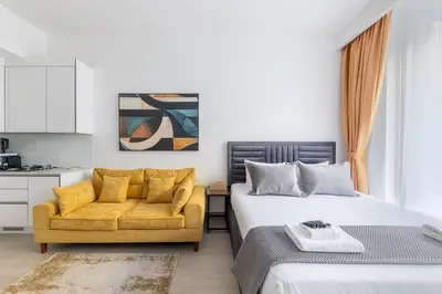 a bedroom with a bed and a yellow couch at Luma Studio in Jumeirah Village Circle in Dubai