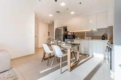 a kitchen with white cabinets and a table and chairs at Balcony Overlooking the Swimming Pool, Just Minutes from the Park, Town Square Safi 1A, Al Yelayiss 2 by Deluxe Holiday Homes in Dubai