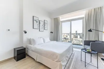 a white bedroom with a large bed and a couch at HAVN - New Studio Apartment in Bloom Towers, JVC in Dubai