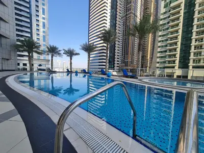 a swimming pool with palm trees and tall buildings at Classy Upgraded High Floor Prime Location in Dubai