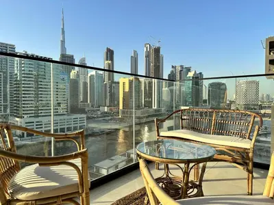 a balcony with two chairs and a glass table at Bright Studio Burj Khalifa & Canal Views Pool in Dubai