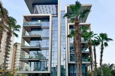 a tall building with palm trees in front of it at Serene Seaside Stay - 2BR in Bluewaters with Sea View in Dubai
