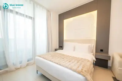 a bedroom with a bed and a large window at Blue Breeze - Trendy Studio with Balcony & Stylish Interiors in Dubai