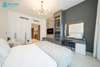 a bedroom with a bed and a desk and a tv at Blue Breeze - Trendy Studio with Balcony & Stylish Interiors in Dubai