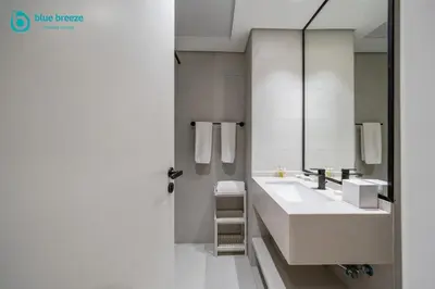 a white bathroom with a sink and a mirror at Blue Breeze - Trendy Studio with Balcony & Stylish Interiors in Dubai