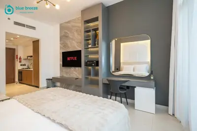 a bedroom with a bed and a desk with a mirror at Blue Breeze - Trendy Studio with Balcony & Stylish Interiors in Dubai