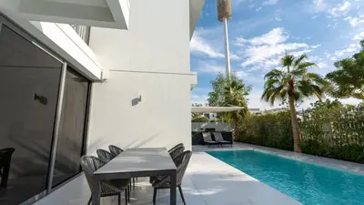 a patio with a table and chairs next to a swimming pool at Lavish Sidra 3 Villa, 4BR plus M,Private Pool BBQ in Dubai