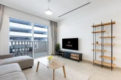 a living room with a couch and a tv at Livbnb-Stylish 1B with Spacious Balcony in JVC in Dubai