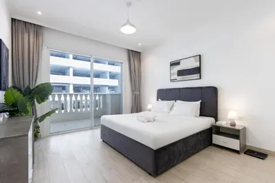 a bedroom with a large bed and a large window at Livbnb-Stylish 1B with Spacious Balcony in JVC in Dubai
