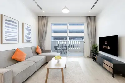 a living room with a couch and a tv at Livbnb-Stylish 1B with Spacious Balcony in JVC in Dubai