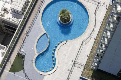 an overhead view of a large swimming pool with a plant at Stylish 1-Bedroom Apartment with Premium Amenities in Dubai