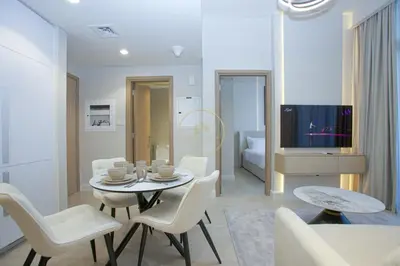 a living room with a table and chairs and a television at Standard 2BHK located in Azizi riviera 46 in Dubai