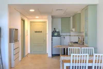 a kitchen with a refrigerator and a table with chairs at Spacious studio in a green oasis in Dubai