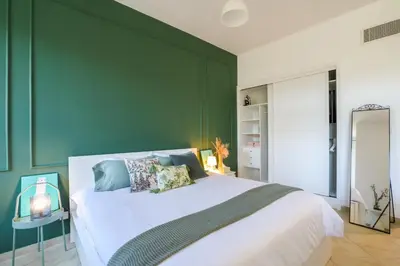 a bedroom with a large bed with green walls at Spacious studio in a green oasis in Dubai