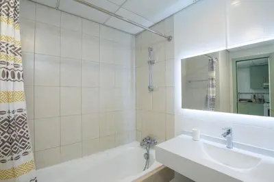 a bathroom with a sink and a tub and a mirror at Spacious studio in a green oasis in Dubai