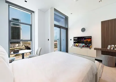 a white bedroom with a large bed and a tv at Chic Studio with Top Amenities in Dubai