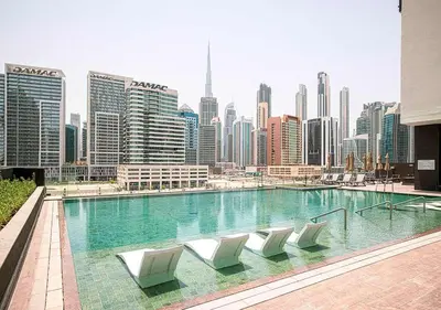 a swimming pool with white chairs and a city skyline at Chic Studio with Top Amenities in Dubai