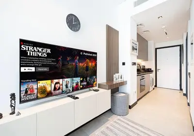 a large flat screen tv on a wall in a kitchen at Chic Studio with Top Amenities in Dubai