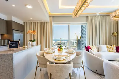 a kitchen and living room with a table and chairs at Lux Designer 2BR - Grand Bleu - Waterfront Living in Dubai