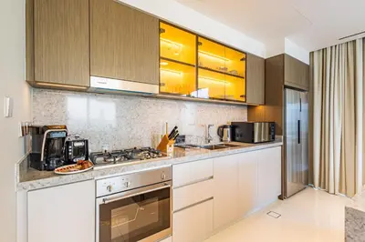 a kitchen with white cabinets and a stove top oven at Lux Designer 2BR - Grand Bleu - Waterfront Living in Dubai