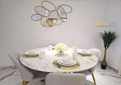 a dining room table with chairs and a round table with glasses at Elegant 2BR in Dubai Hills Estate Hosted by Desert City Stays in Dubai