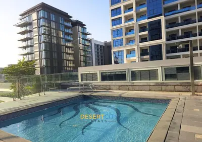 a swimming pool in front of a tall building at Elegant 2BR in Dubai Hills Estate Hosted by Desert City Stays in Dubai