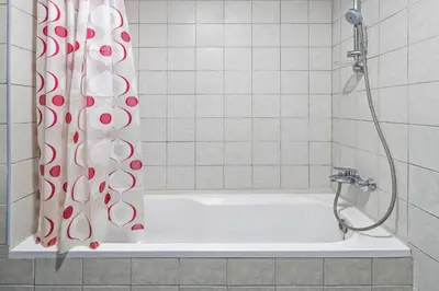 a shower with a red and white shower curtain in a bathroom at 021 - Discovery Gardens (Building 18) in Dubai