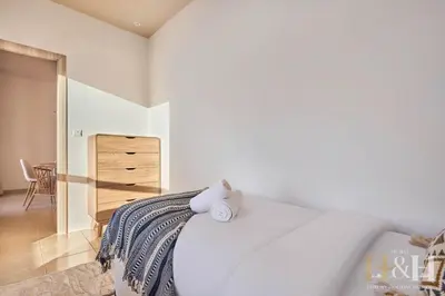 a white bedroom with a bed and a dresser at Stunning views of Dubai Sea, Dubai Eye & JBRWalk in Dubai