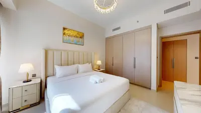 a bedroom with a large white bed and a chandelier at Act One Act Two - Exquisite One Bed in Downtown in Dubai