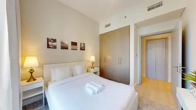 a white bedroom with a large white bed with two lamps at Forte Tower - Aesthetic Three Bedroom in Downtown in Dubai