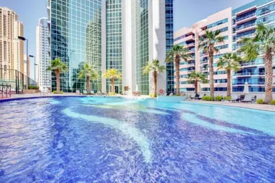 a large swimming pool with palm trees and buildings at Vacationer I Hidden Gem in Marina l 3 Bedroom I Yacht Views, Free Pool, Gym & Wi-Fi in Dubai