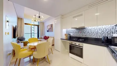 a kitchen and dining room with a table and yellow chairs at Aykon Tower - Calm One Bed in Business Bay in Dubai