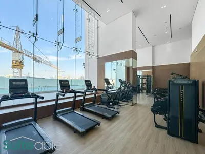 a gym with several treadmills and a large window at Perfect Blend of Comfort and Cozy 1 Bedroom in JVC in Dubai