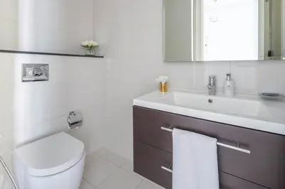 a white bathroom with a toilet and a sink at Frank Porter - Damac Majestine in Dubai