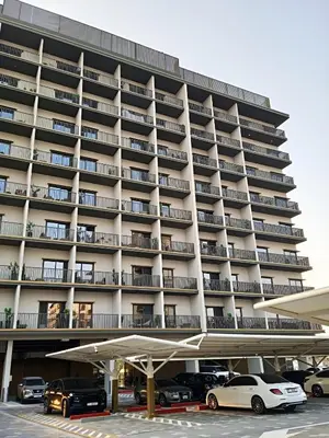 a large apartment building with cars parked in a parking lot at Brand New Studio 15 mins drive from Business Bay in Dubai