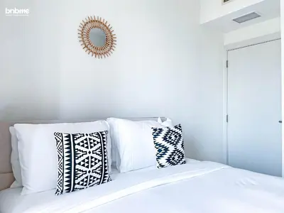 a bedroom with white walls and a bed with pillows at bnbmehomes - Golf Tower 1 in Dubai