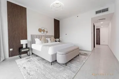 a white bedroom with a large bed and a chair at Beautiful & Spacious 3 Bedroom Wmaids In Marina in Dubai