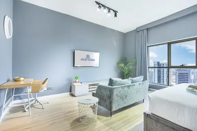 a living room with a bed and a couch and a desk at Stylish & Compact Home in the Heart of the JVC in Dubai