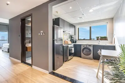 a kitchen with a stainless steel refrigerator and a table at Stylish & Compact Home in the Heart of the JVC in Dubai