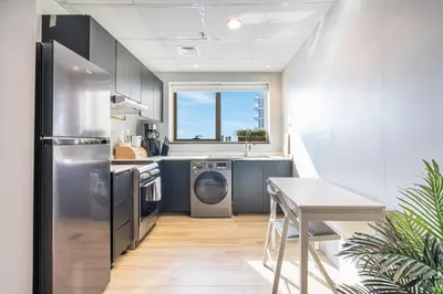 a kitchen with a stainless steel refrigerator and a table at Stylish & Compact Home in the Heart of the JVC in Dubai