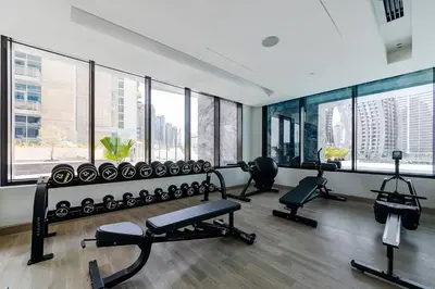 a gym with cardio equipment in a building with windows at Cozy 1BR apartment Binghatti Canal Business Bay in Dubai