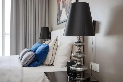 a bedroom with a bed with a black lamp on a table at Modern 1BR apartment Artesia DAMAC Hills in Dubai